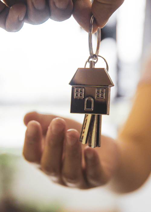 photo d'une main mettant un porte-clé avec une maison dans une autre main