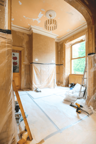 photo d'une pièce en cours de rénovation dans une maison ancienne, avec des murs et des sols recouverts de bâches plastique